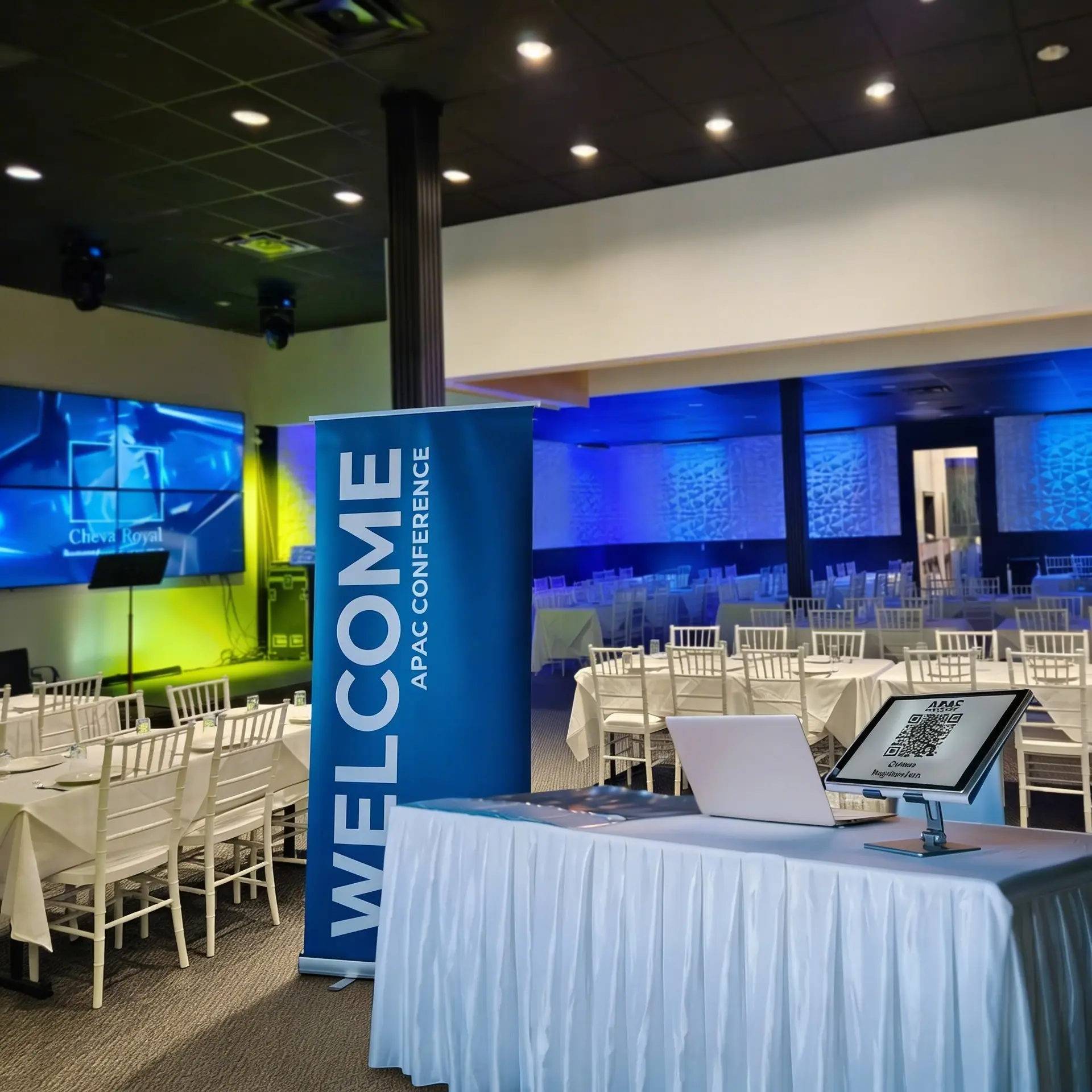 Welcome banner displayed prominently in a conference setting with tables and chairs arranged for attendees.